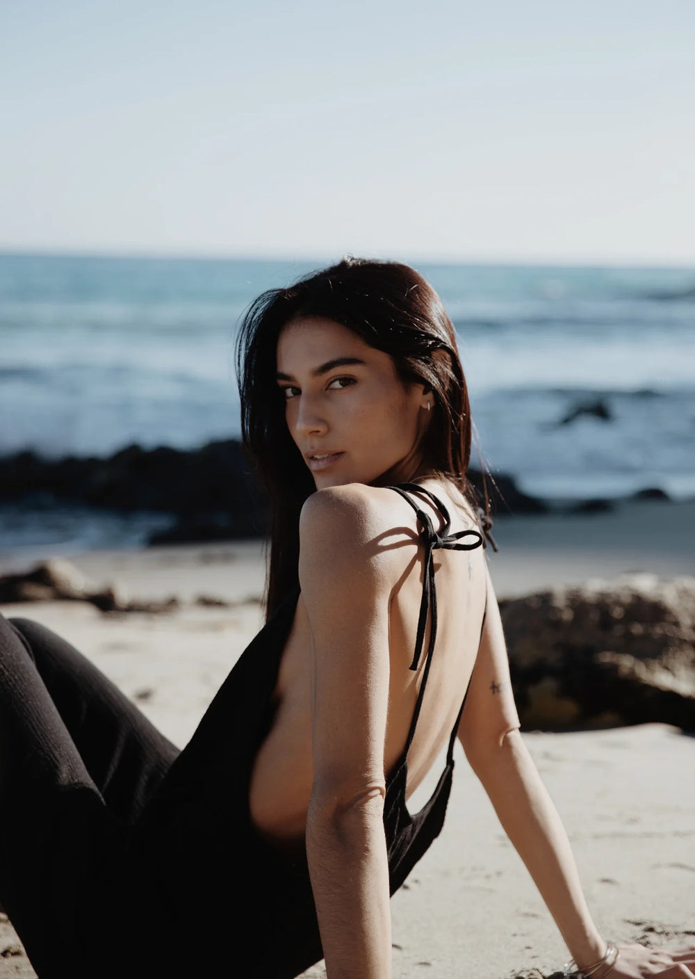 Woman at the beach wearing the  Black Gauze Some Beachy Overalls by Stillwater,