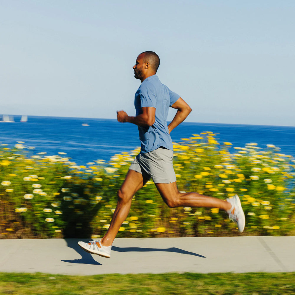Man running while wearing the Free Fly Men's 5.5" Bamboo-Lined Active Breeze Shorts in the color Cement