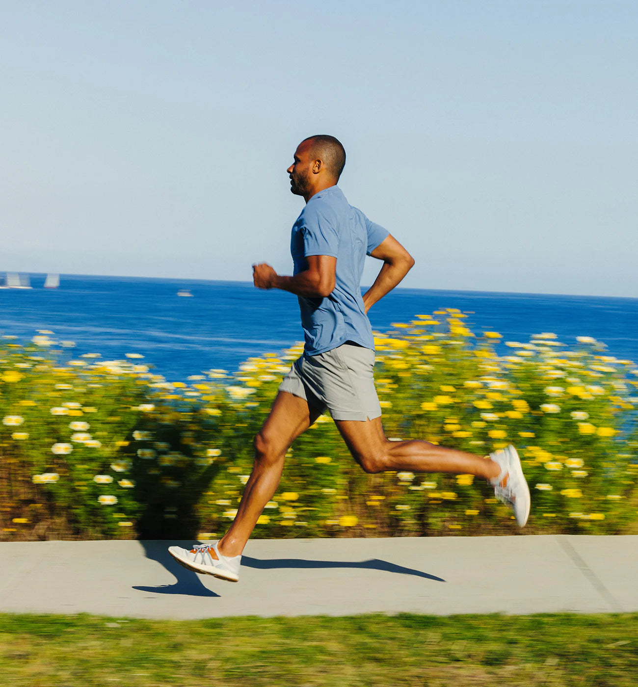 Man running while wearing the Free Fly Men's 5.5" Bamboo-Lined Active Breeze Shorts in the color Cement
