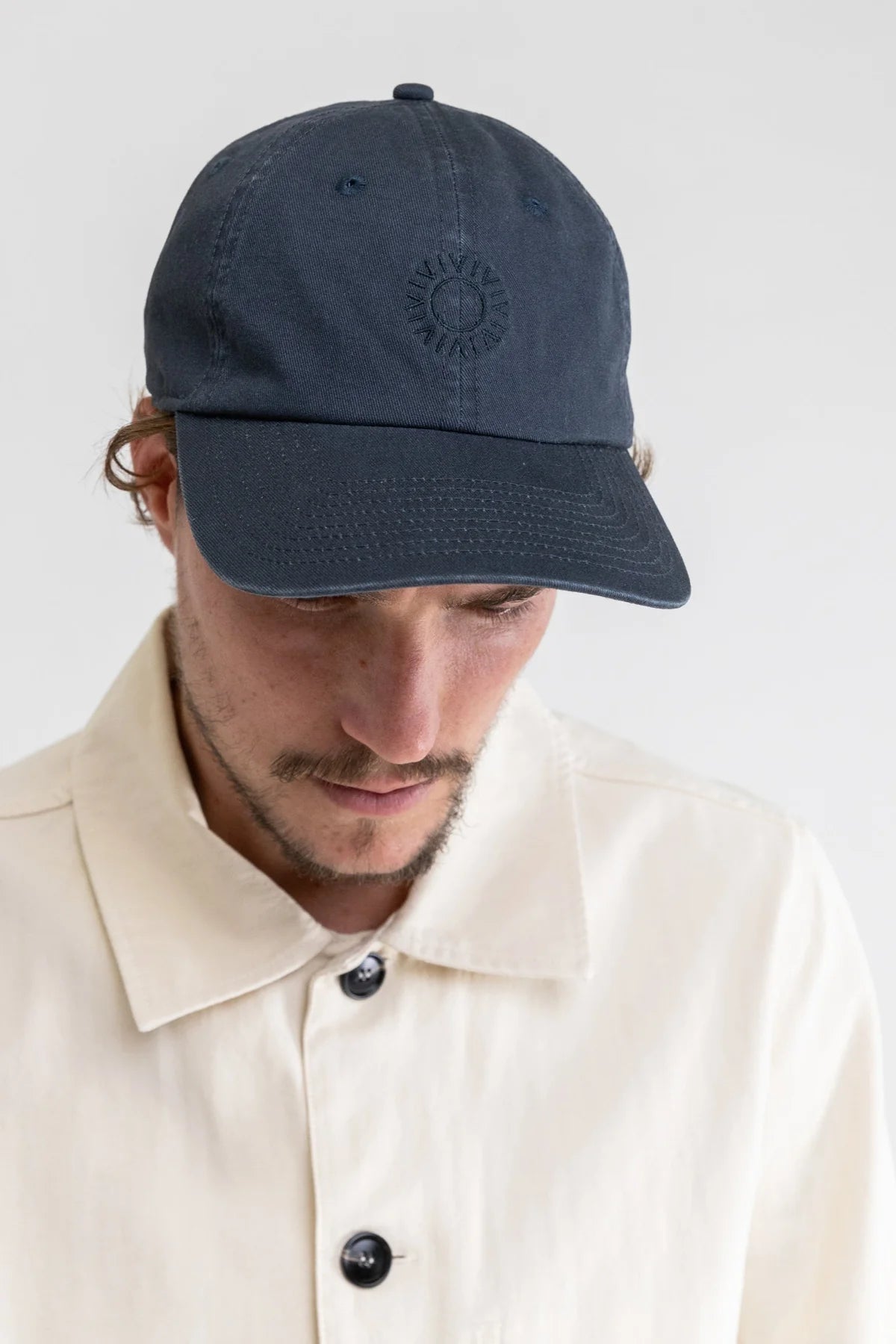 Front view of man wearing a 5 panel cap by Rhythm in color Worn Navy