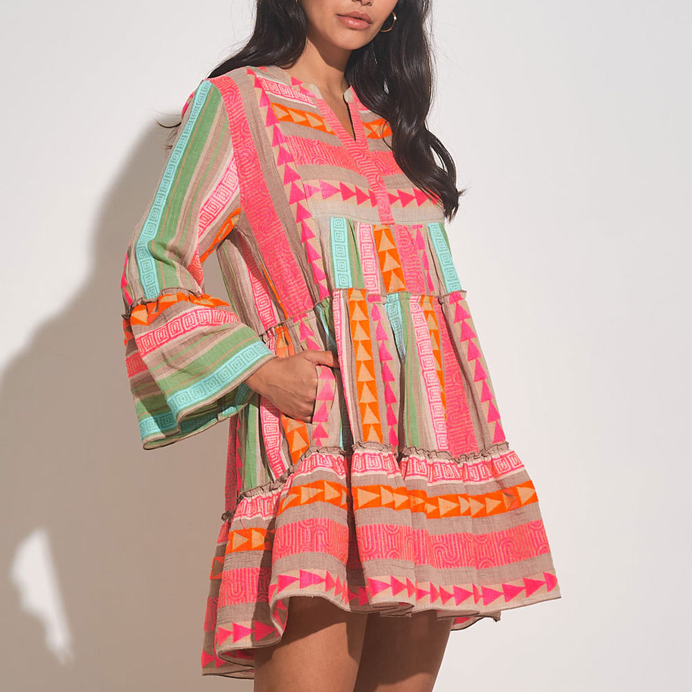 Front side view of woman wearing a multi color mini dress with a a babydoll silhouette and pockets