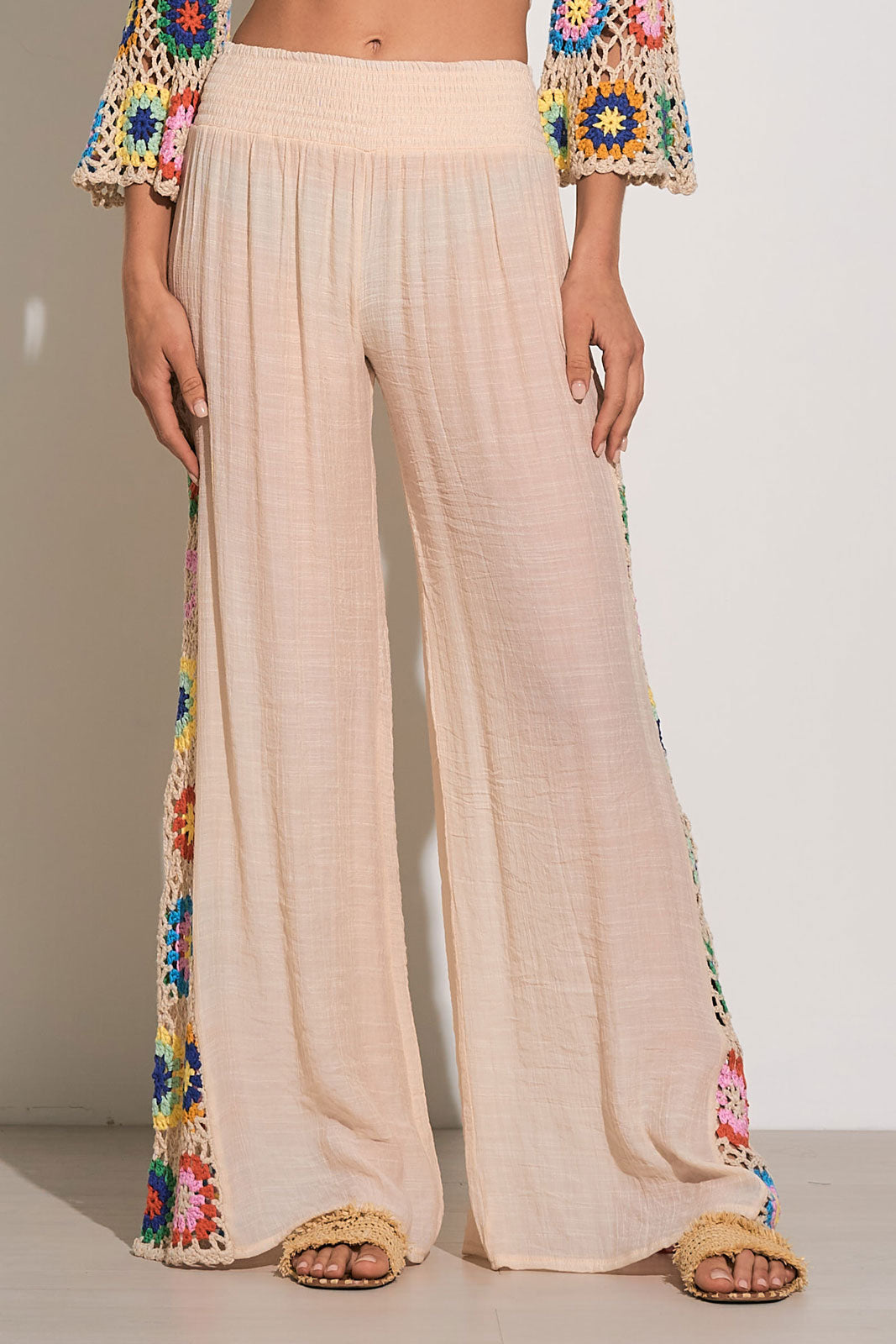 Front view of tan, wide leg pants with multicolor crochet details at the side and an elastic waistband