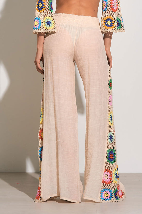 Back view of tan, wide leg pants with multicolor crochet details at the side and an elastic waistband