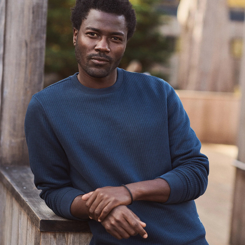 A man wearing the navy Corbet Quilted Crewneck sweater from Marine Layer