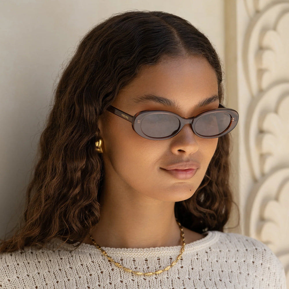 
                      
                        A woman wearing the FREYRS Mimi Women's Oval Sunglasses in the style Brown
                      
                    