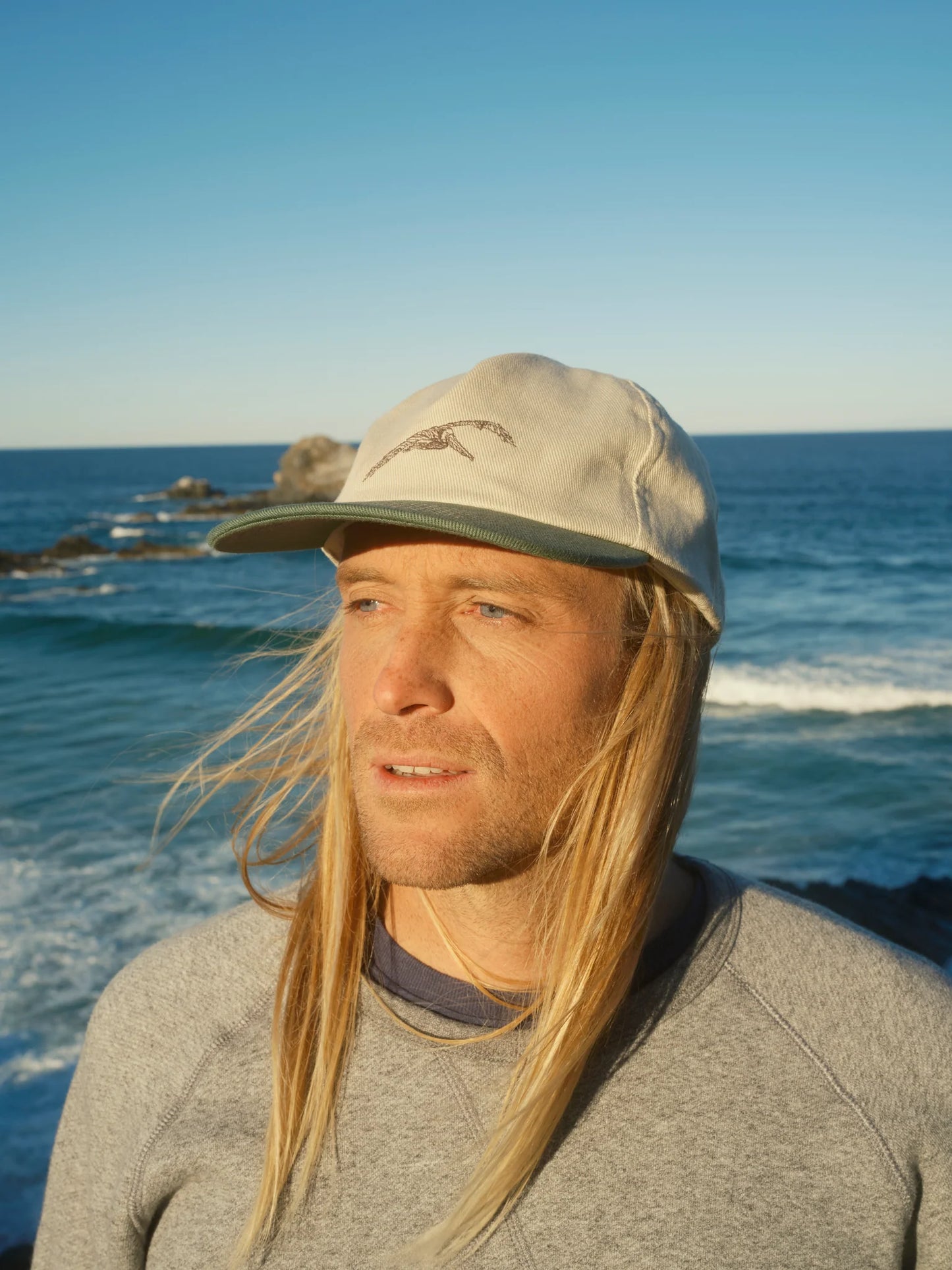 front view of man wearing the Flite Hat by Mollusk in front of the ocean