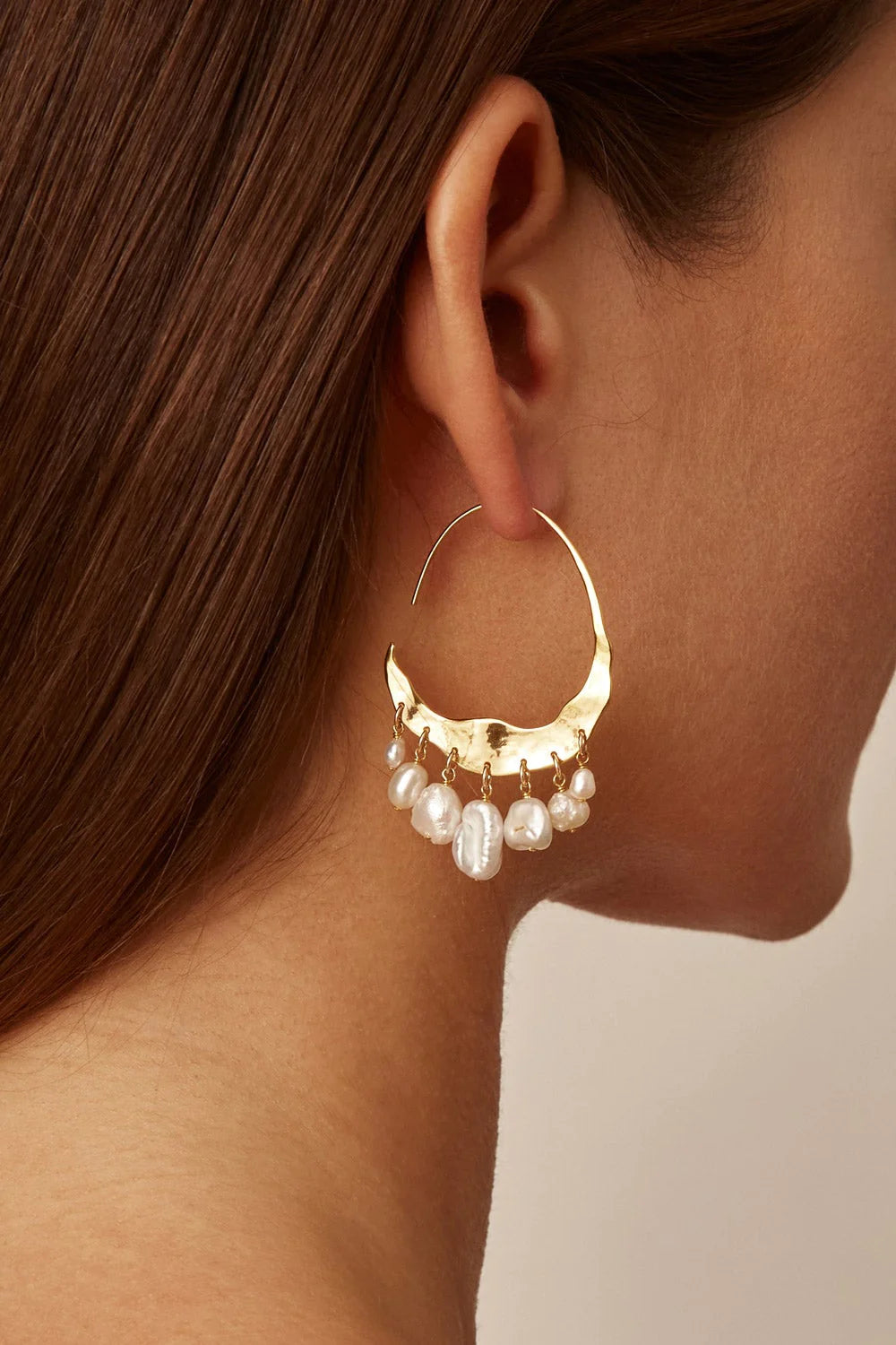 Woman wearing Chan Luu's Crescent White Pearl and Gold Hoop Earrings