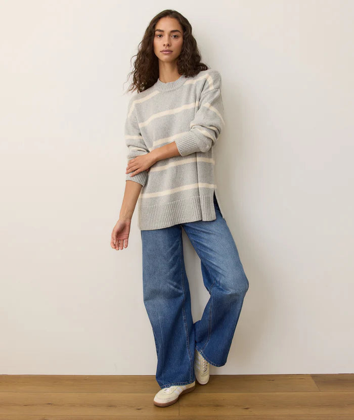 Woman wearing a striped sweater and blue jeans against a plain background
