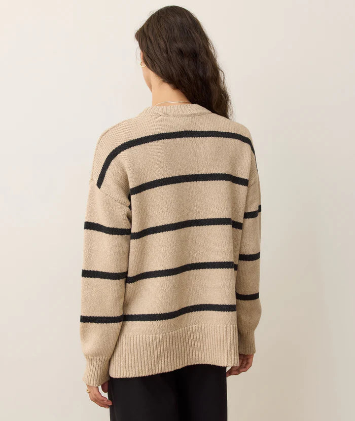 Person wearing a beige sweater with black stripes on a plain background