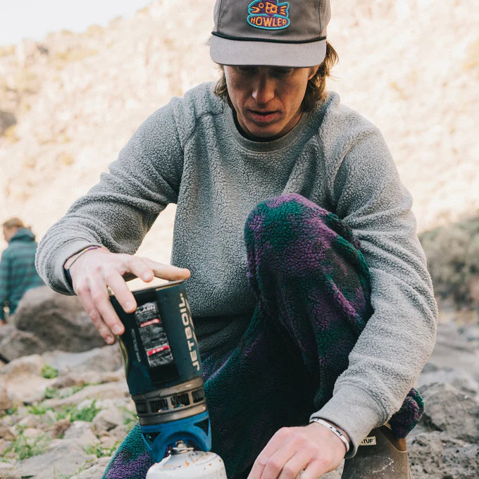 A man outside camping while wearing the Eleos Fleece Crewneck by Howler Bros