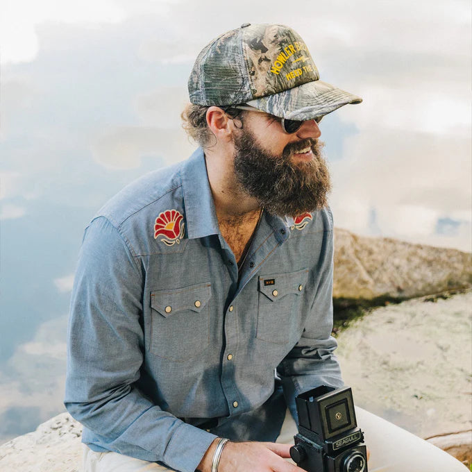 A man outside wearing the Fresh Blooms Crosscut Deluxe Snapshirt by Howler Bros