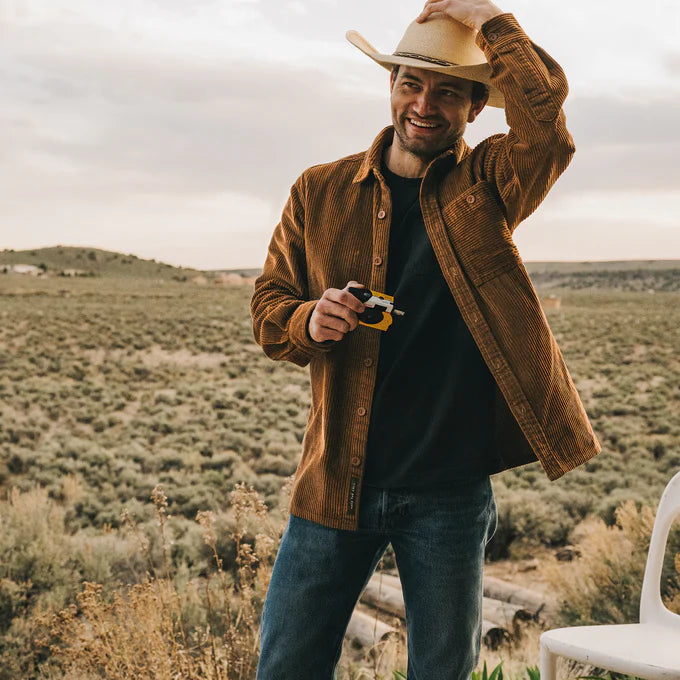 A man on a ranch wearing the Brown Iquitos Overshirt by Howler Brothers