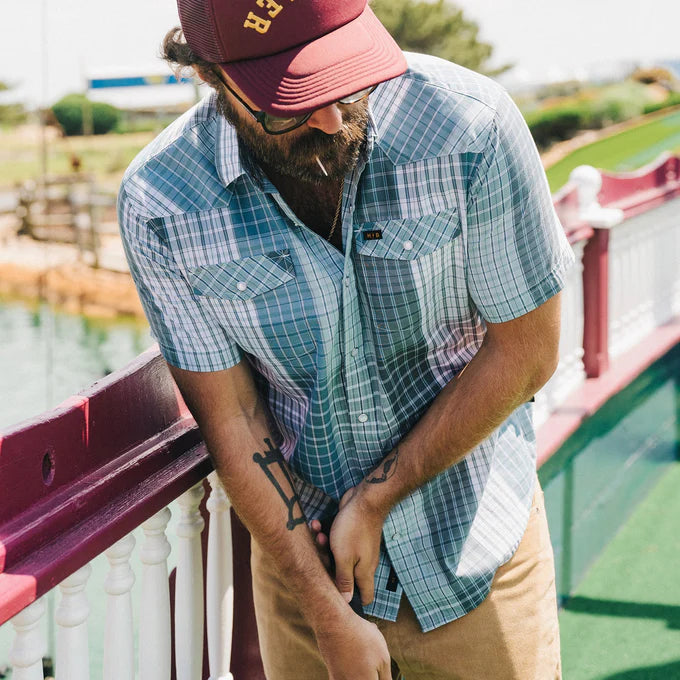 A man outside wearing the Cottage Plaid Blues H Bar B Snapshirt  by Howler Bros