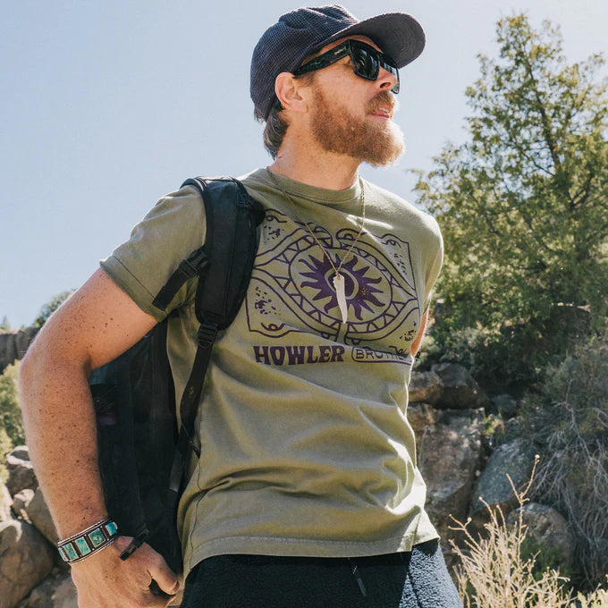 
                      
                        A man wearing the Sun Drinker Cotton T-Shirt by Howler Brothers while hiking
                      
                    