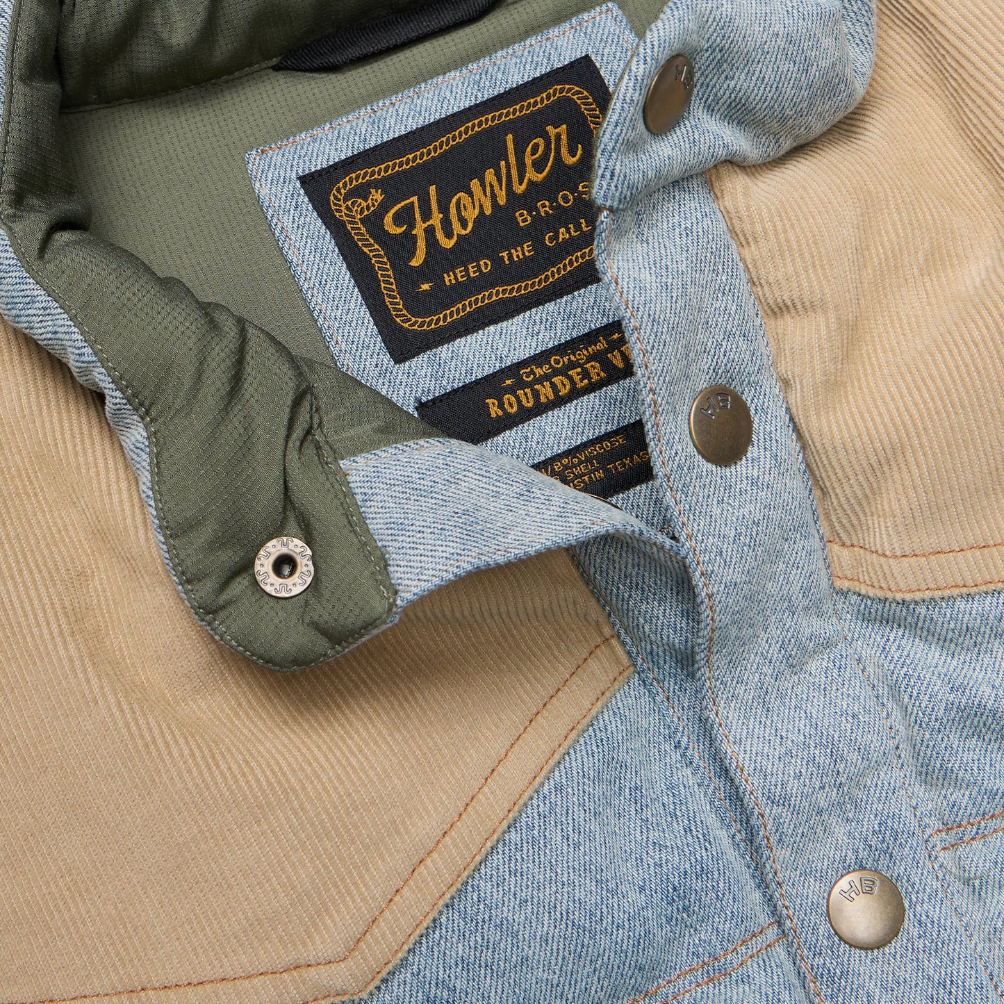Close-up of the Denim Rounder Vest with visible Howler Bros labels on a beige and blue fabric background.