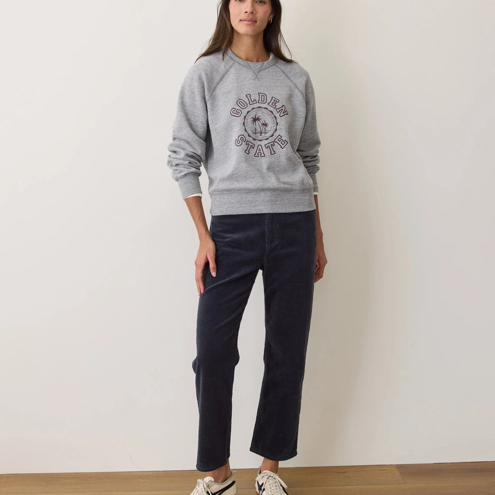 A woman wearing the Marine Layer Charlie Corduroy Straight Pant in the color Navy, paired with a crewneck sweatshirt