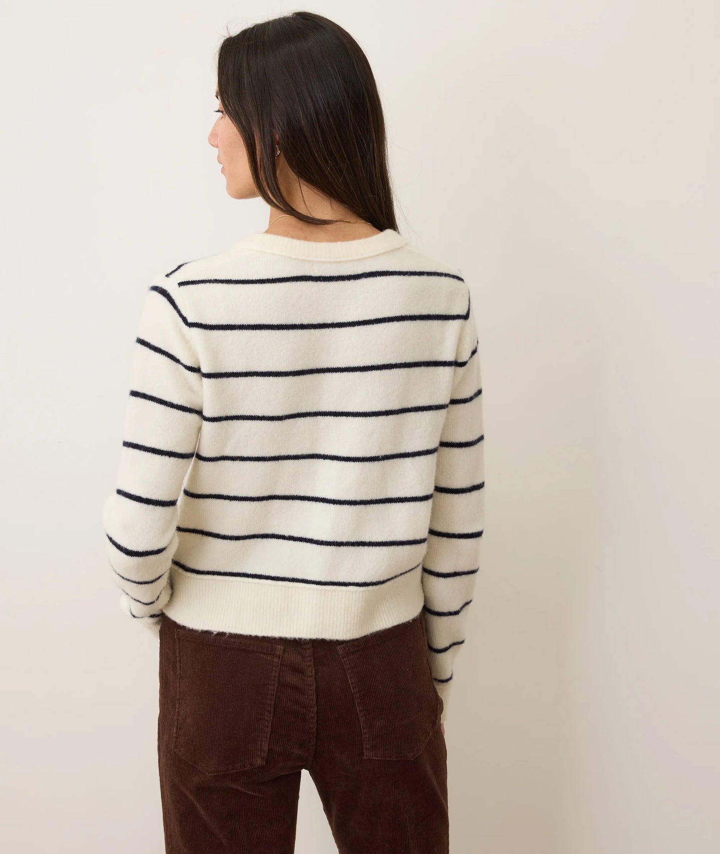 A woman wearing a white cardigan with black stripes