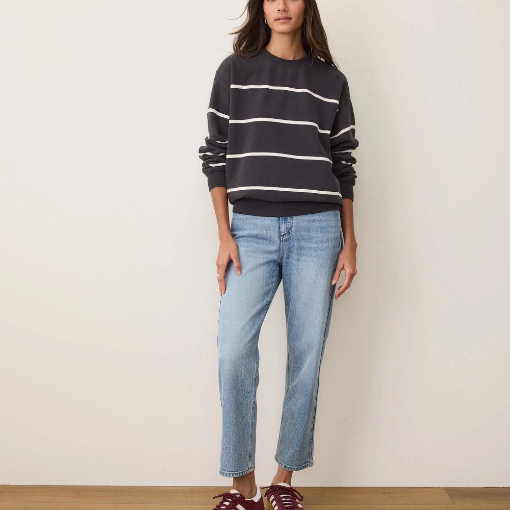 
                      
                        A woman wearing a black oversized crewneck sweatshirt with white stripes from Marine Layer
                      
                    