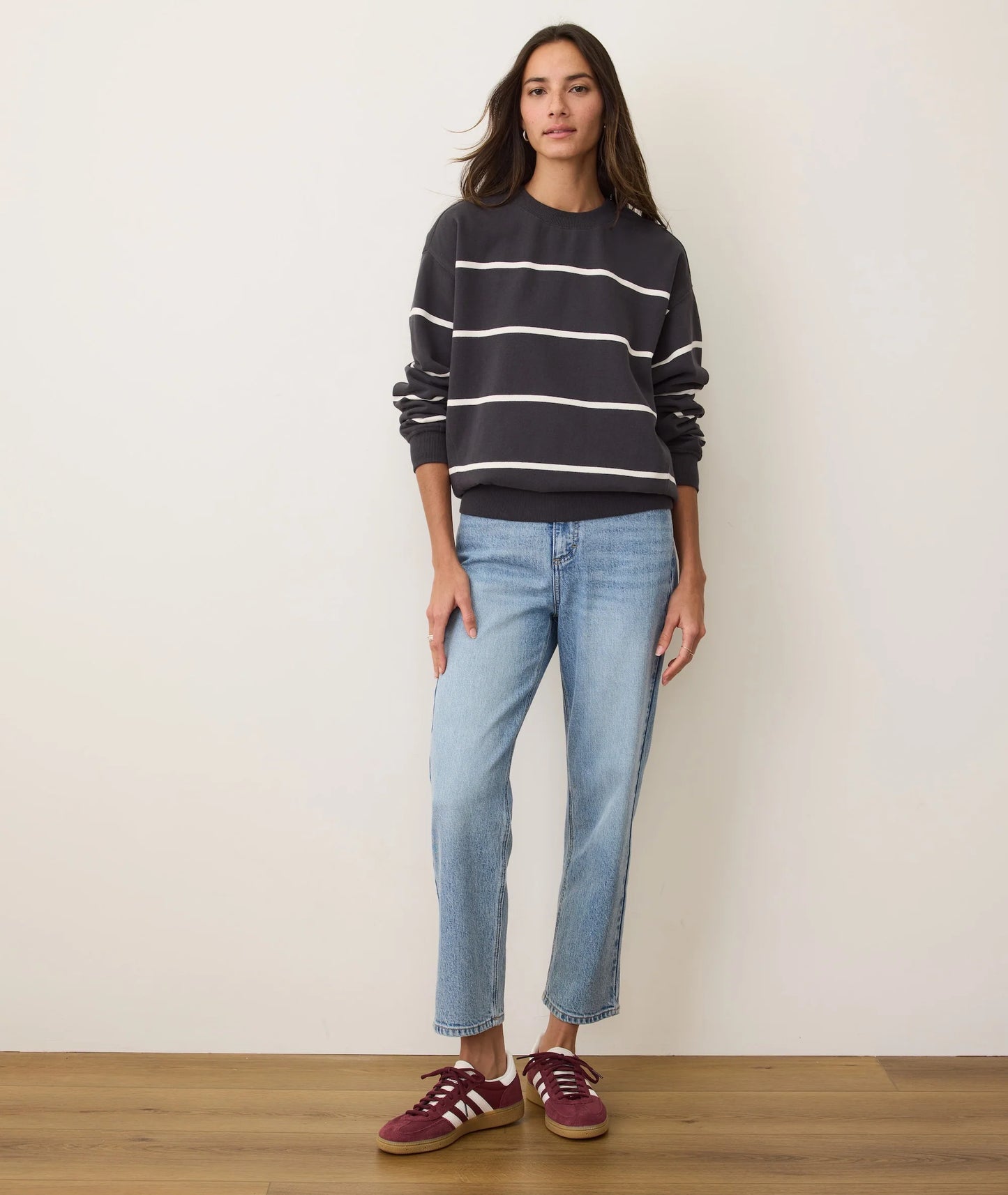A woman wearing a black oversized crewneck sweatshirt with white stripes from Marine Layer