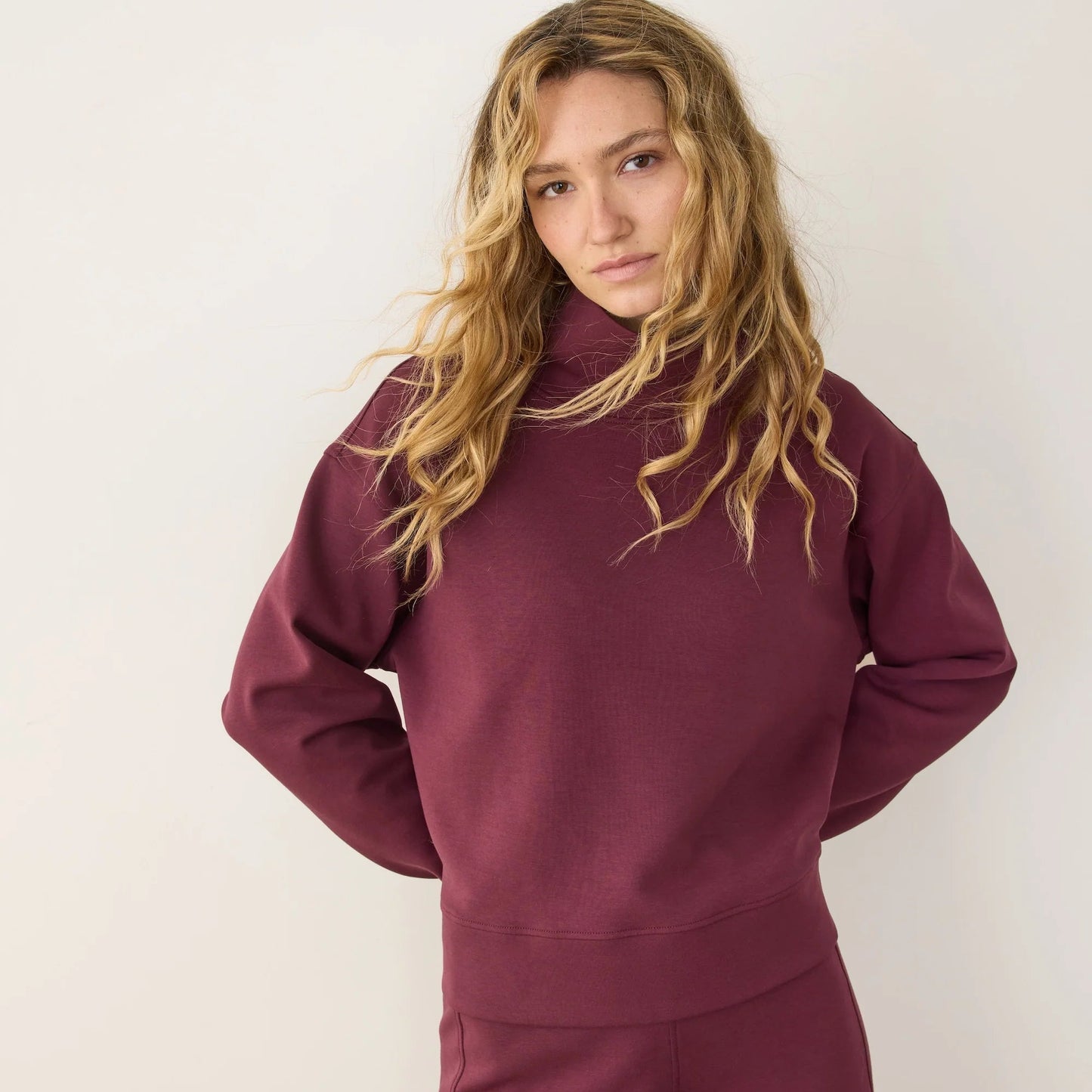 A woman wearing the Marine Layer Nova Mock Neck Sweatshirt in the color Fig