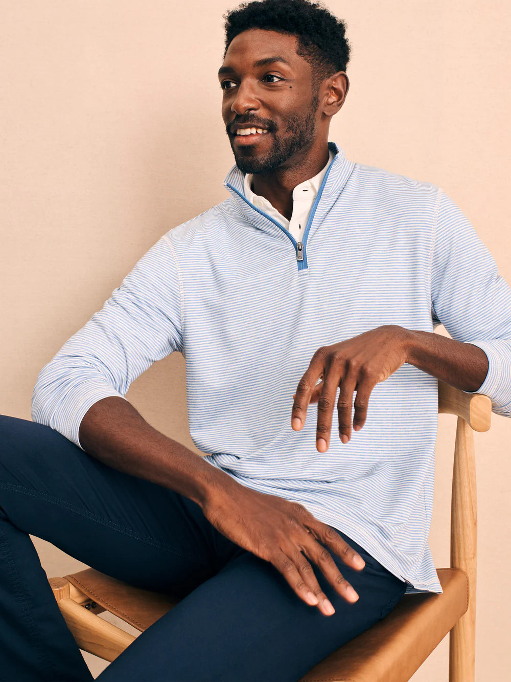 Front view of man wearing a striped quarter zip pullover by Faherty