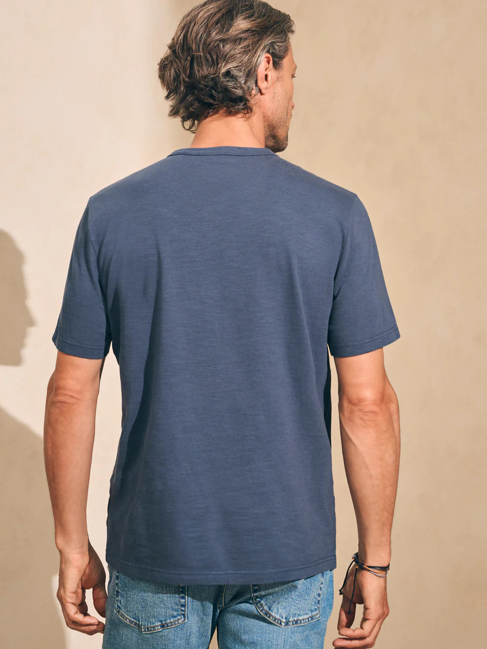 Back view of man wearing the short sleeve Sunwashed Tee in Dune Navy by Faherty