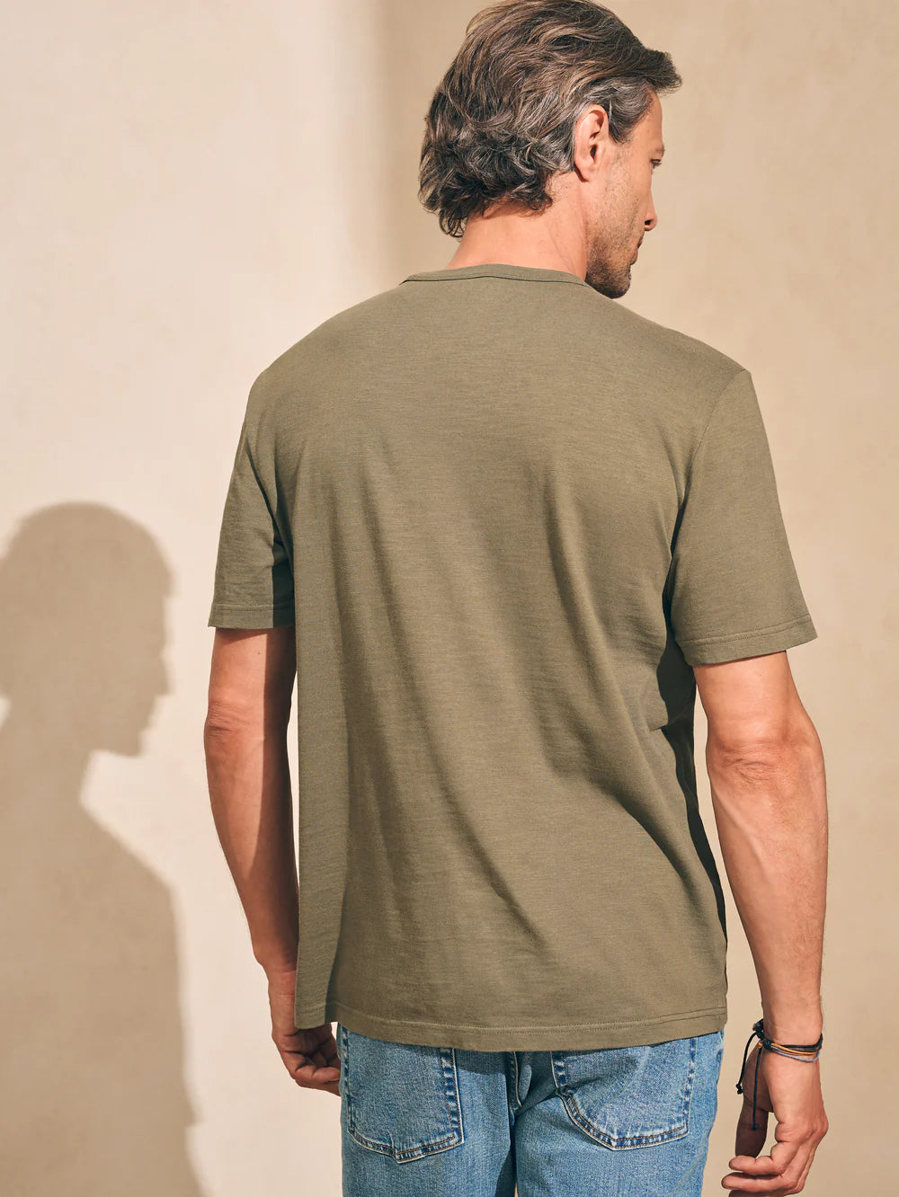 back view of man wearing an olive green short sleeve t-shirt by Faherty