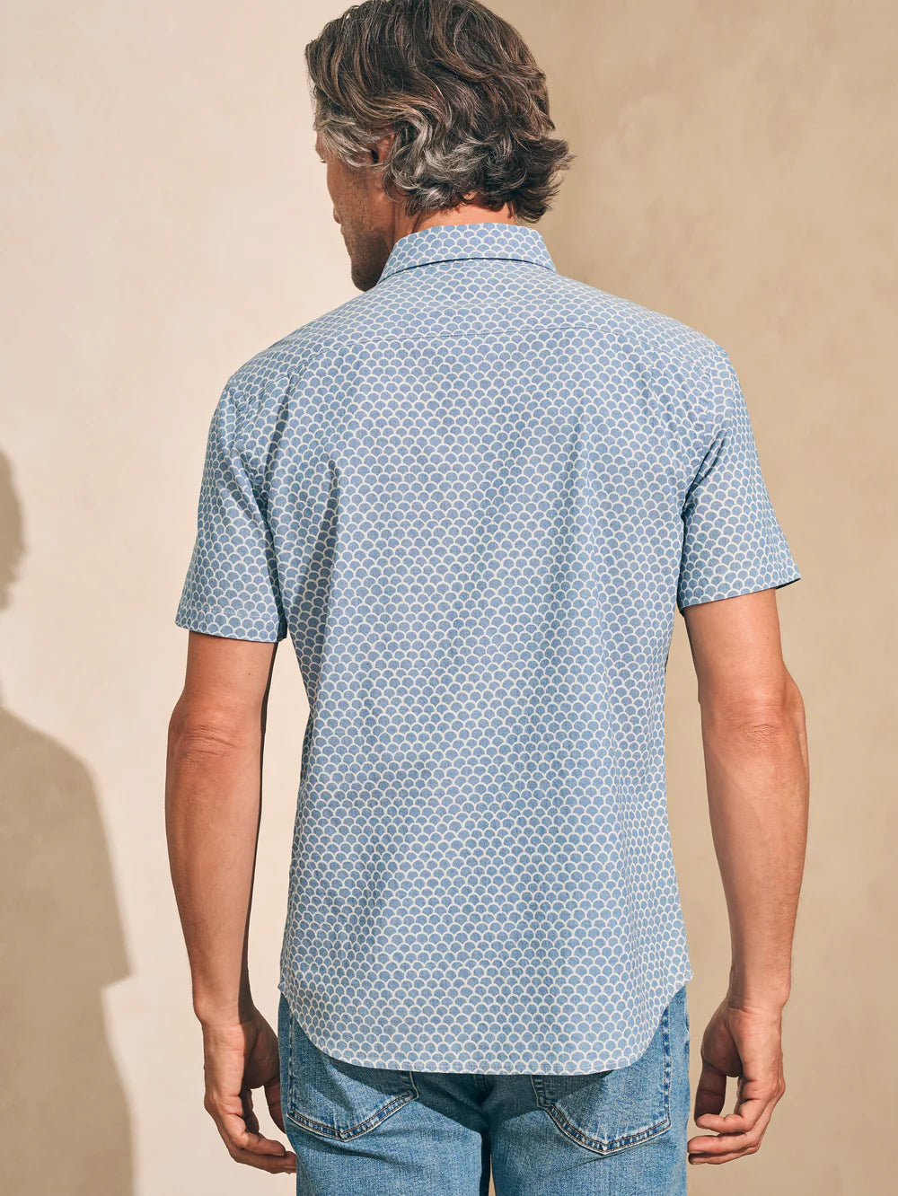 Back view of a man wearing a fishscale print short sleeve button up shirt by Faherty