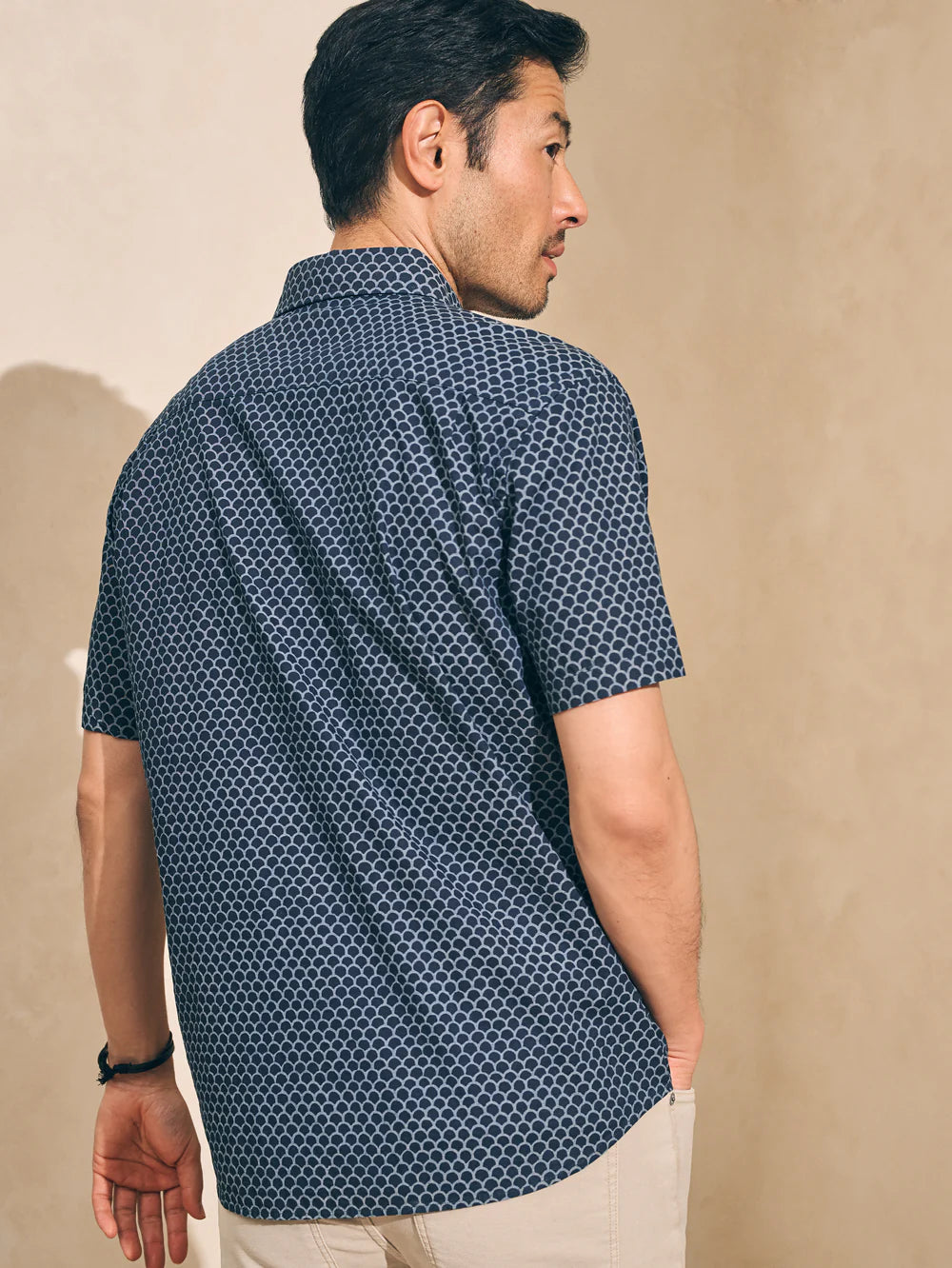 Back view of a man wearing a fishscale print short sleeve button up shirt by Faherty