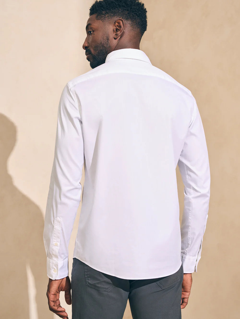 Back view of a man wearing the white long sleeve button up Movement shirt by Faherty