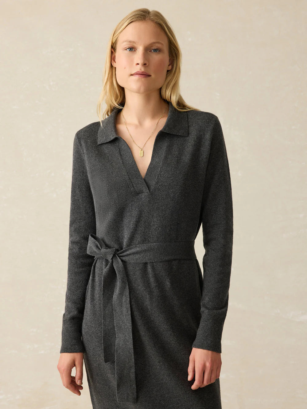 A woman wearing the Medium Grey Heather Jackson Sweater Dress by Faherty, featuring a polo v-neckline and self tie at the waist