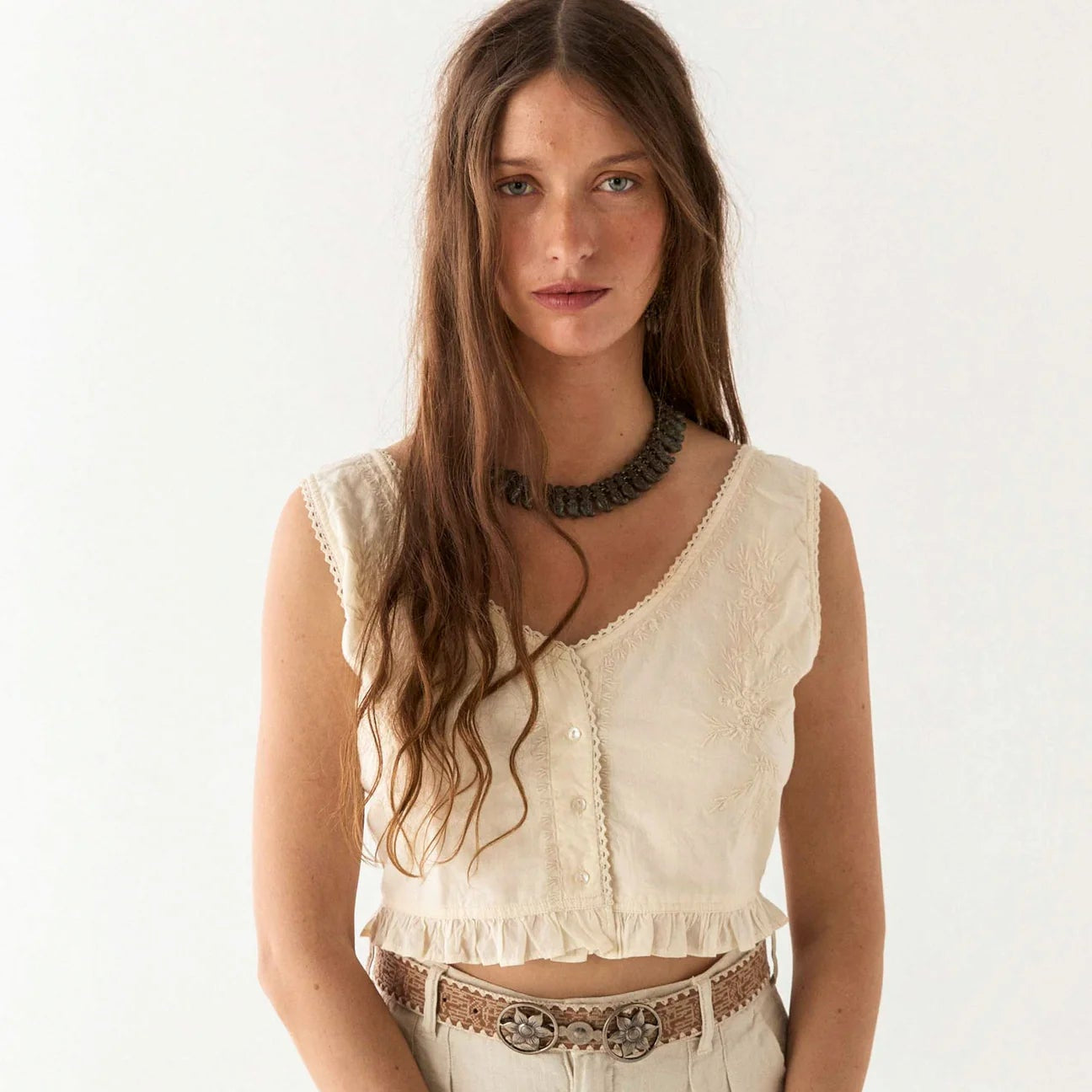 Woman wearing a white sleeveless Meg Blouse from the brand Maison Hotel.