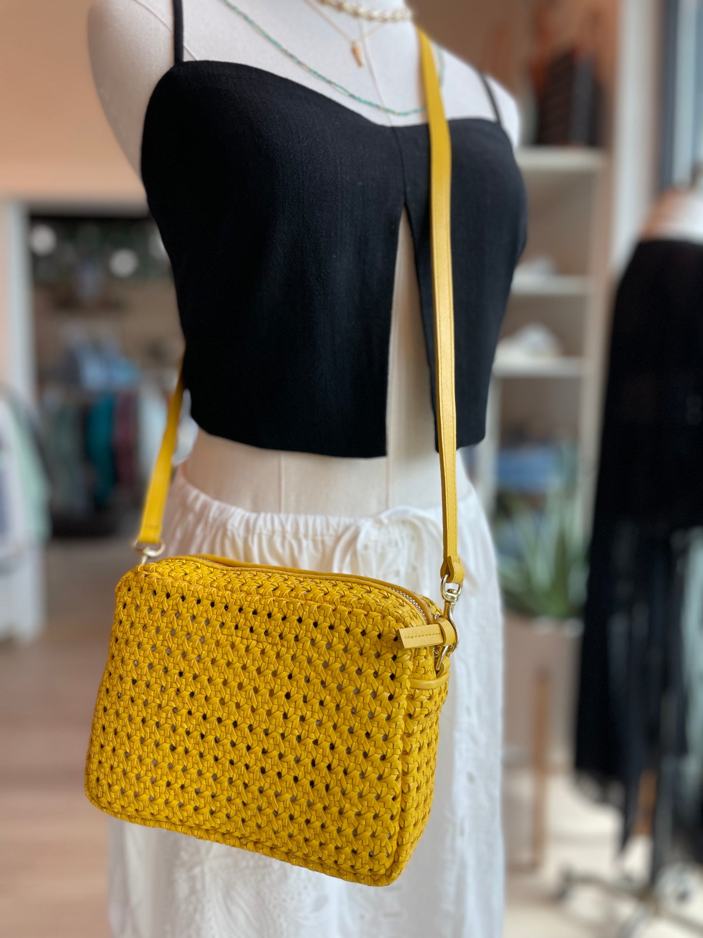 The yellow rattan rectangular midi sac handbag by Clare V being worn as a crossbody