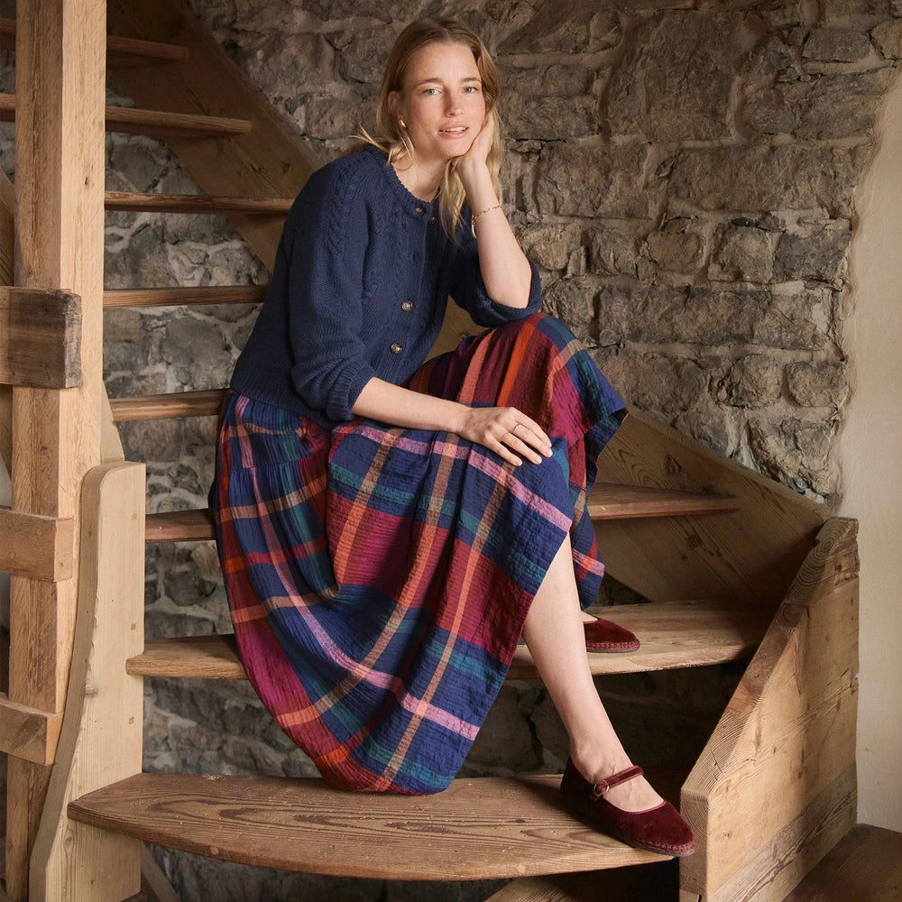 Woman sitting on a wooden staircase wearing a blue sweater paired with the Gia Midi Skirt by Marine Layer