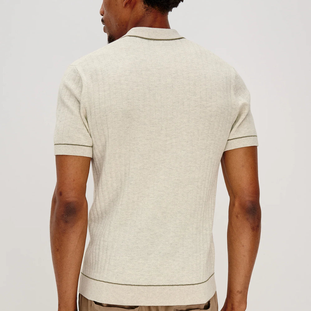 
                      
                        Man wearing a beige patterned polo shirt and beige pants on a white background
                      
                    