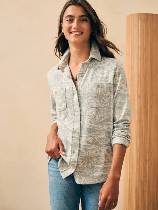 Front, untucked view of woman wearing a long sleeve button up shirt with an understated palm tree and wave print throughout