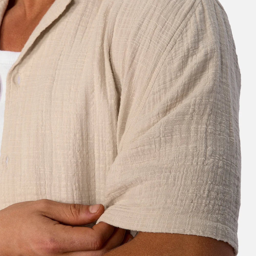 Close-up of a person wearing a beige textured shirt with a white background