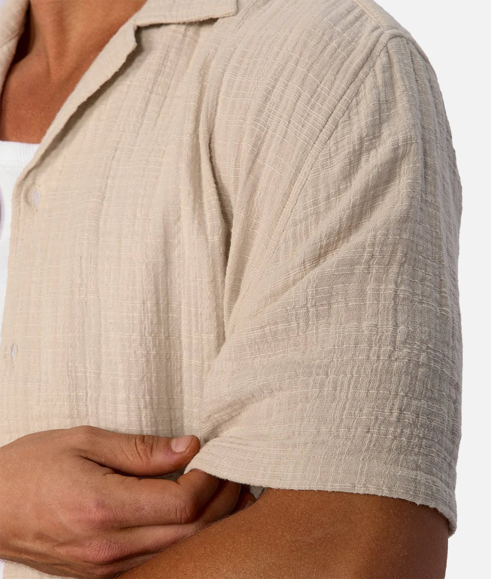 Close-up of a person wearing a beige textured shirt with a white background