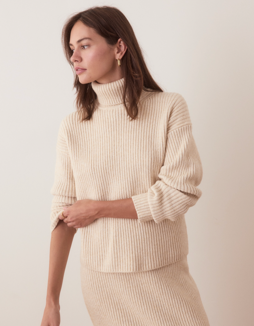 A woman wearing the Isla Knit Turtleneck by Marine Layer in the color Cream