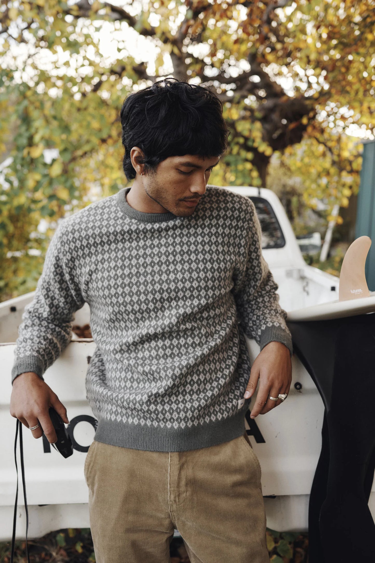Man wearing the Gray Green Katin Check Sweater while standing next to a white truck with autumn trees in the background