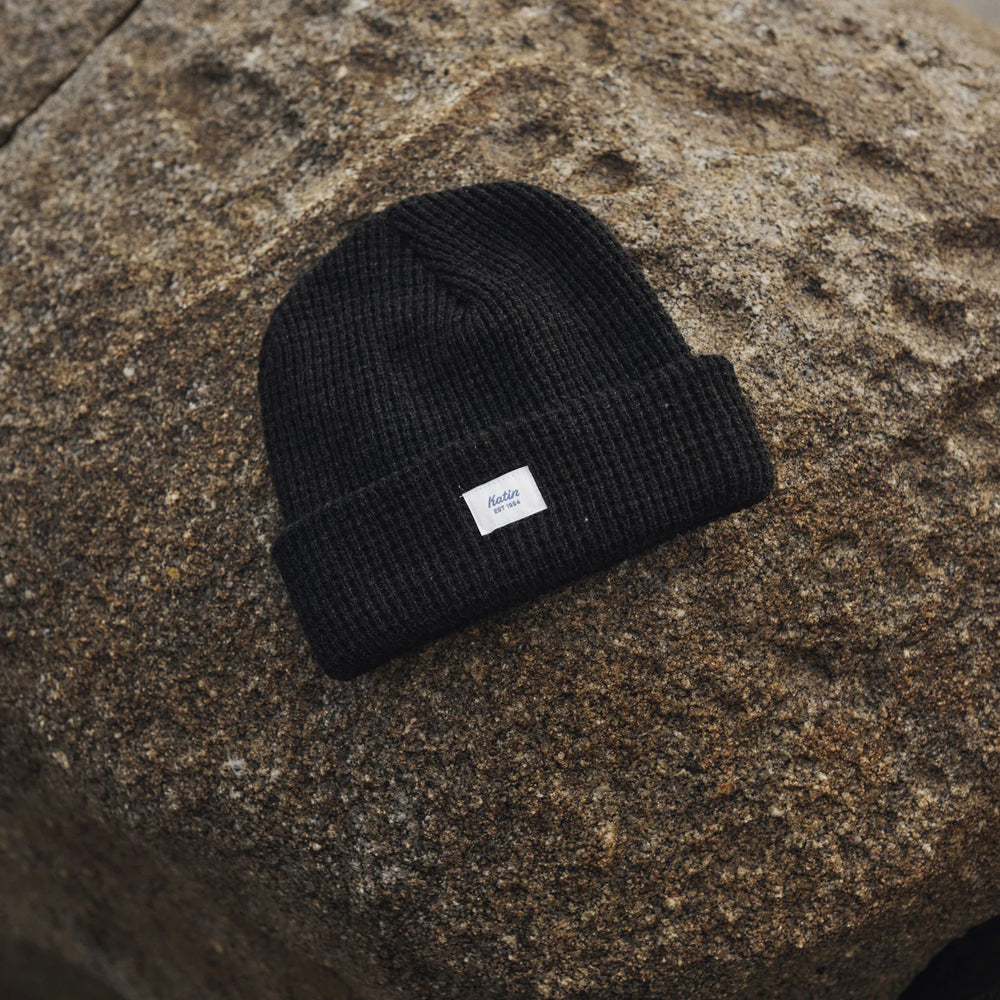 
                      
                        The Black Heather Wade Beanie by Katin on a large rock
                      
                    