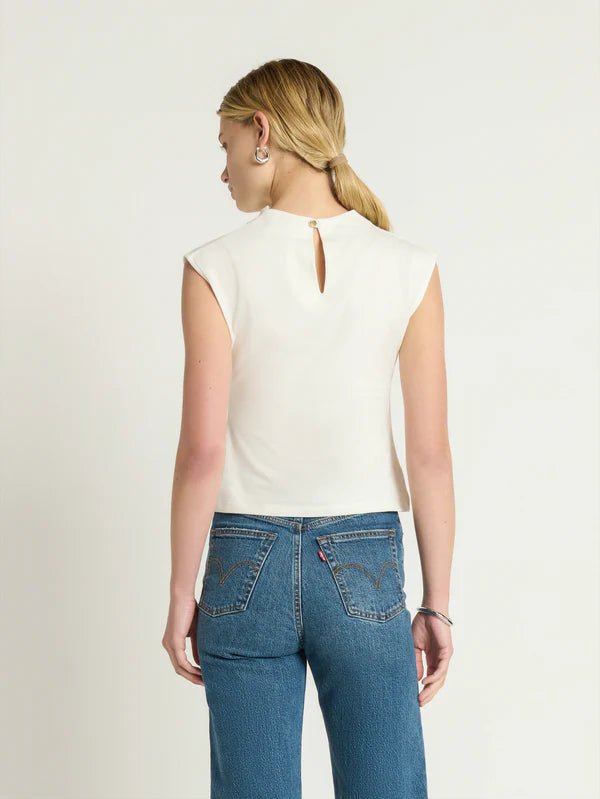 
                      
                        A woman wearing a sleeveless white top with blue jeans
                      
                    