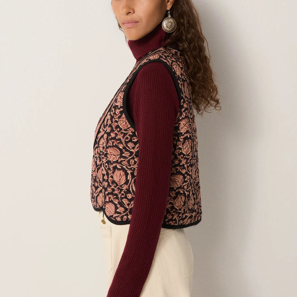 
                      
                        Woman wearing a floral motif embroidered vest over a long sleeve top
                      
                    