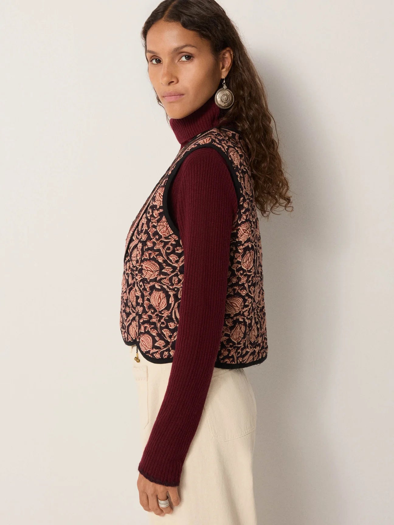 Woman wearing a floral motif embroidered vest over a long sleeve top