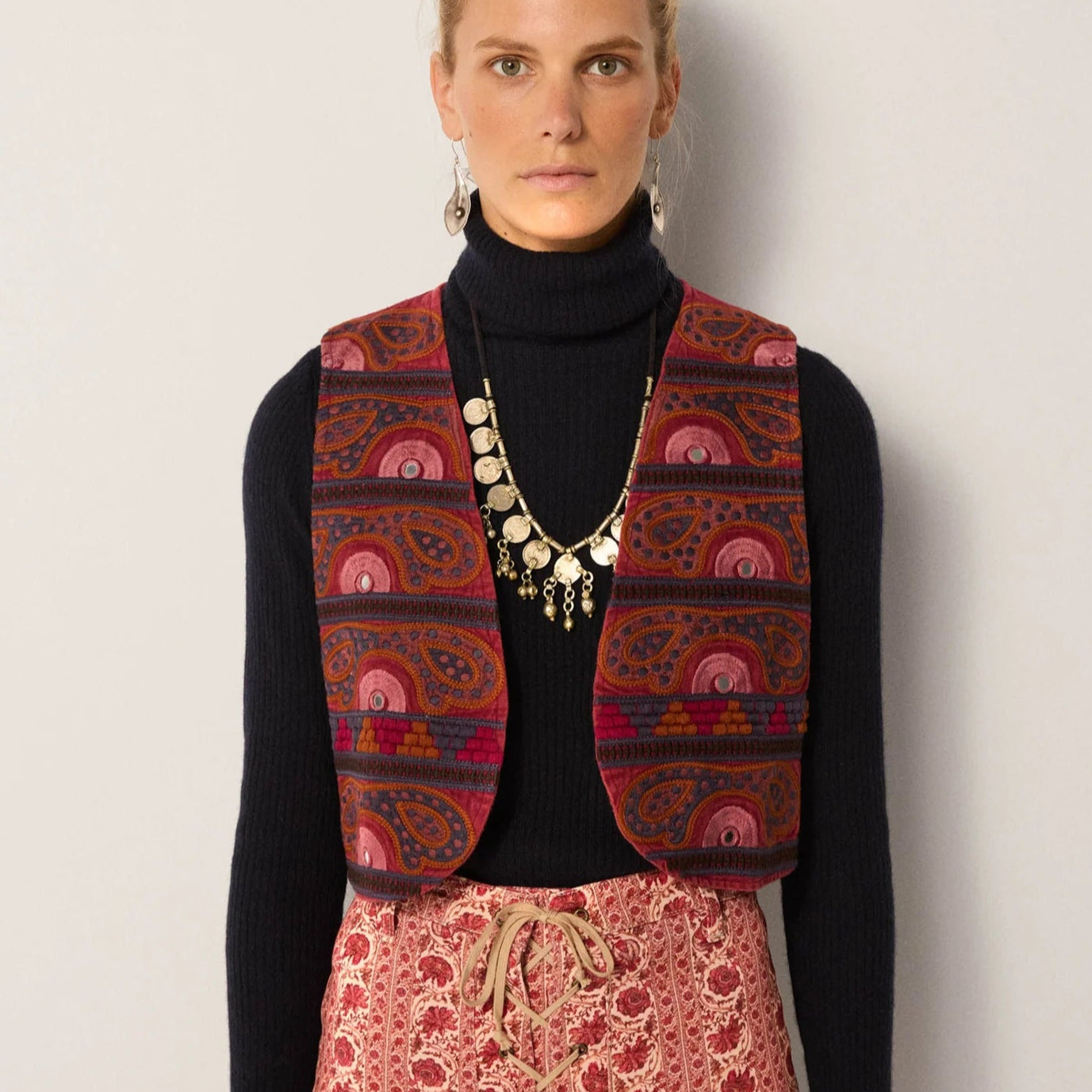 A woman wearing the Gypsy Sun Burgundy Elodie Vest by Maison Hotel layered over a black long sleeve top
