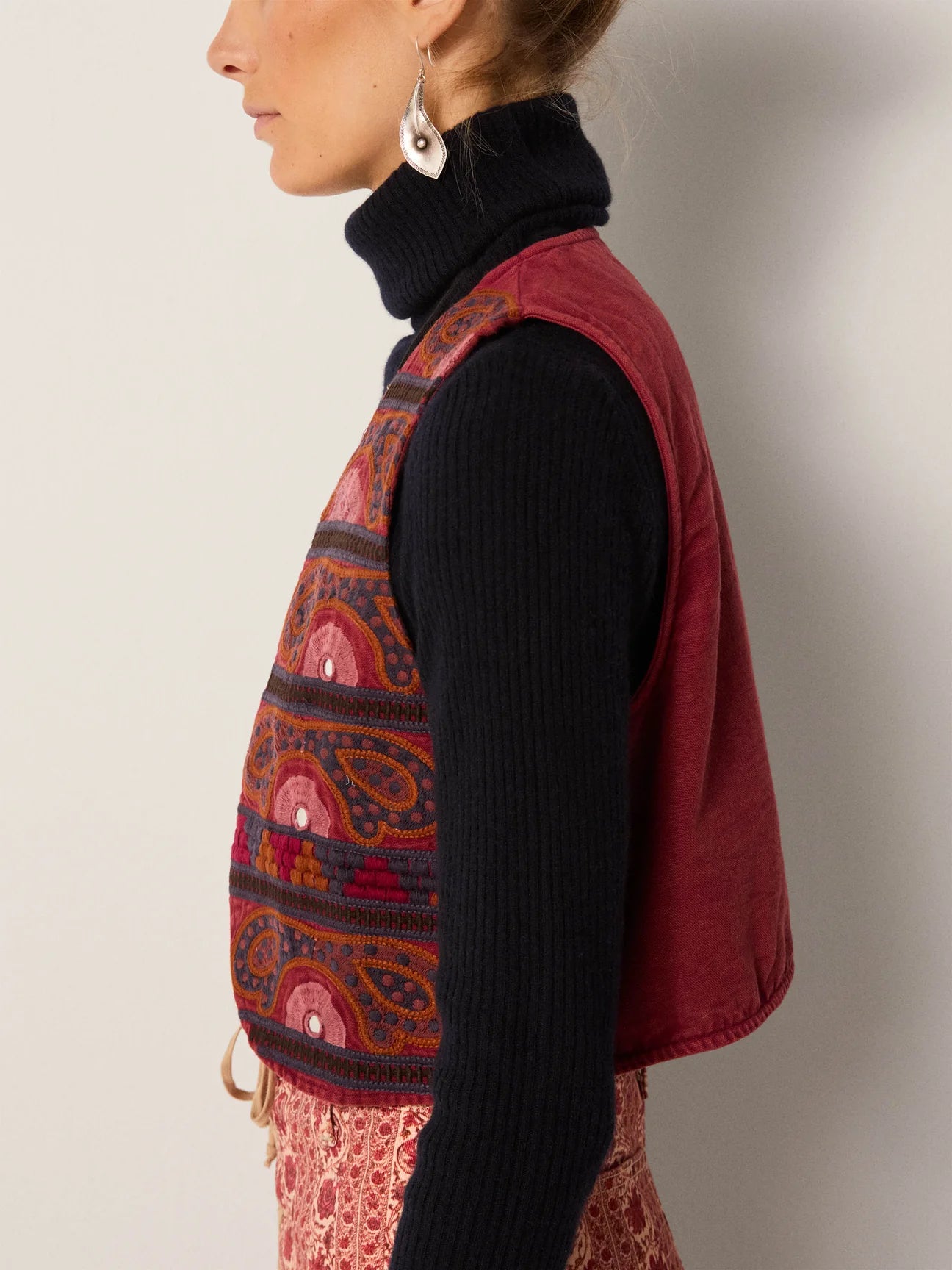 A woman wearing the Gypsy Sun Burgundy Elodie Vest by Maison Hotel over a black turtleneck