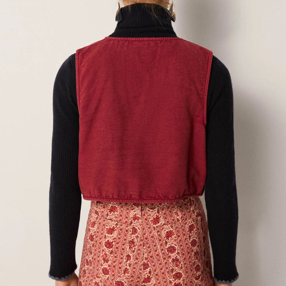 A woman wearing a red vest over a black shirt with patterned pants from Maison Hotel