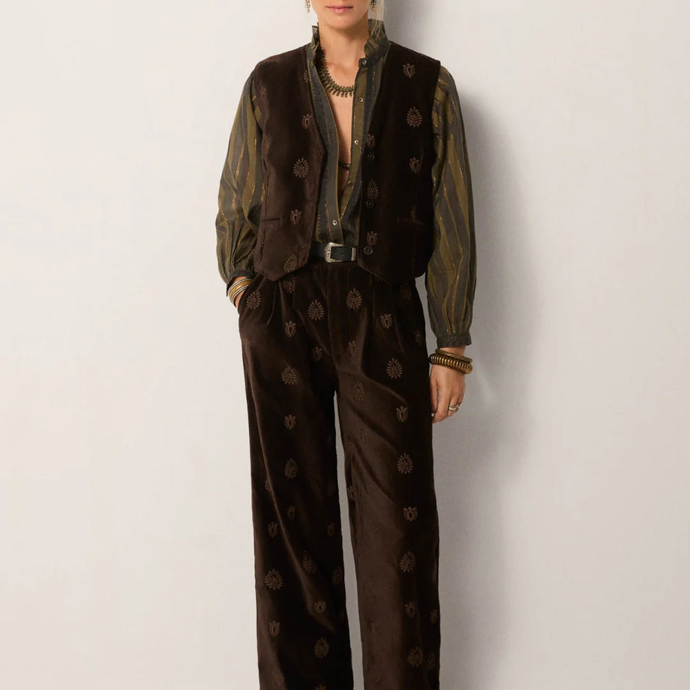 
                      
                        A woman wearing the Velluto Macchiato Kafka Vest by Maison Hotel paired with matching trousers 
                      
                    