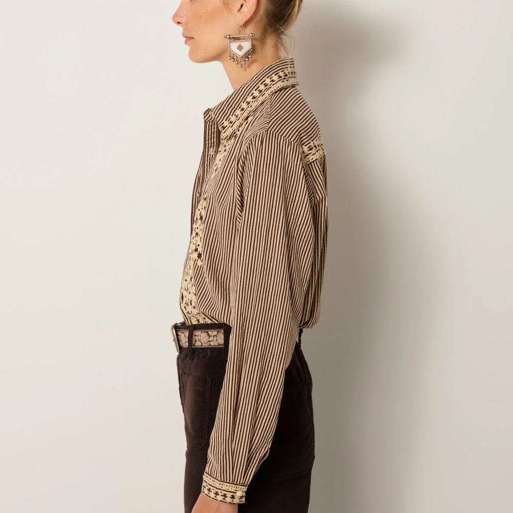 
                      
                        Woman wearing a striped button up shirt with embroidery
                      
                    