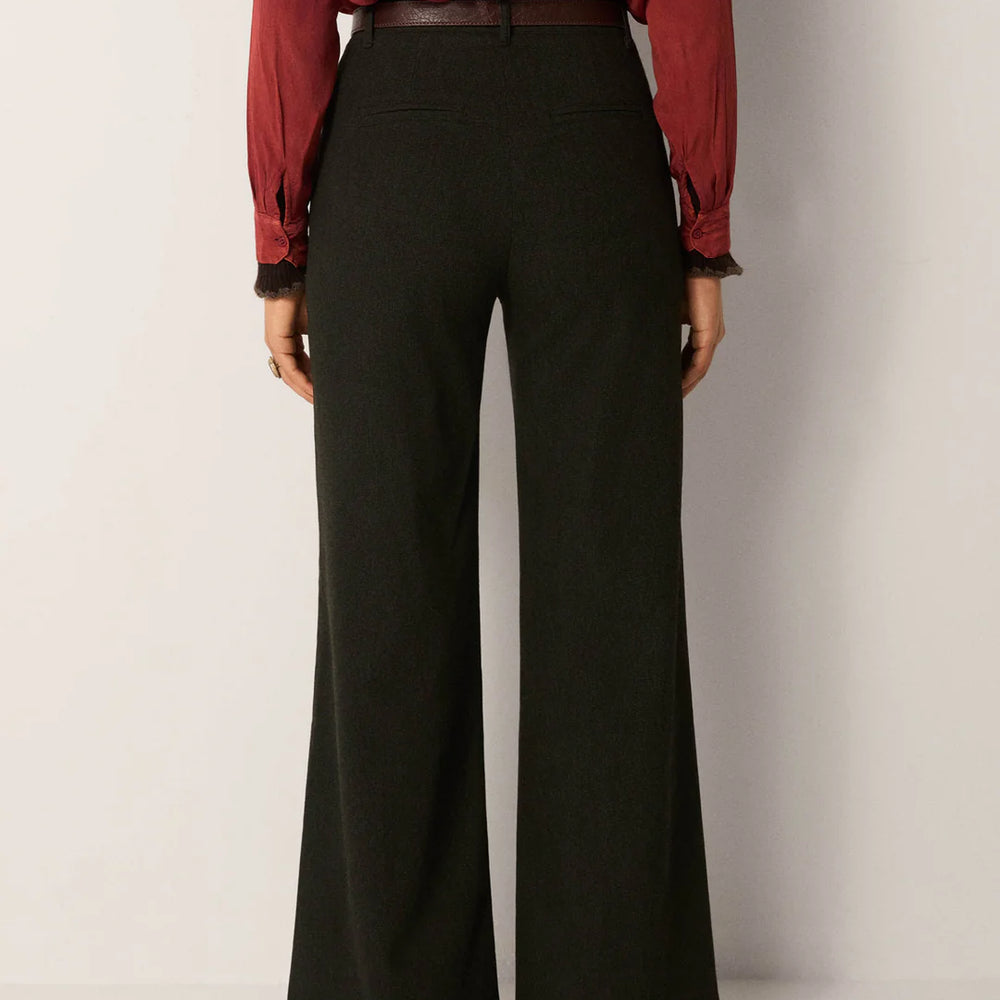 Person wearing a red patterned blouse and dark green wide-leg pants from Maison Hotel
